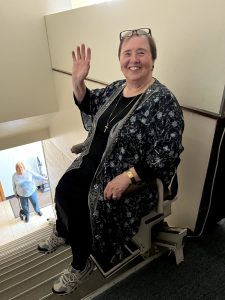 woman waves from chair transport on stairs